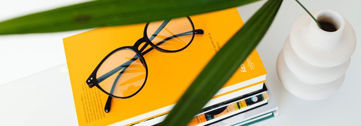 Eye Doctor Cleveland TN Desinger Frames A pair of glasses sitting on a yellow book.