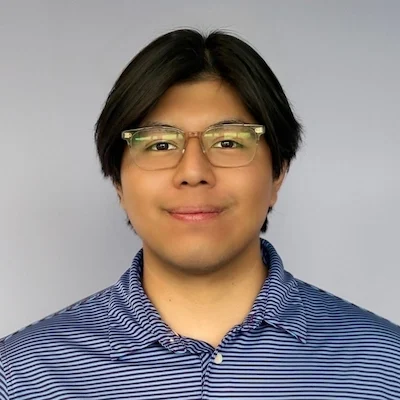 Eduardo smiling in front of a purple wall.