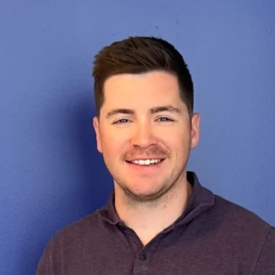 Eye Doctor Brainerd Rd Chattanooga TN Zach Meet The Team Zach smiling in front of a purple wall.
