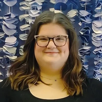 Emma smiling while wearing glasses.
