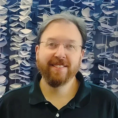 Lee smiling while wearing glasses.