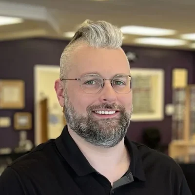 Daniel smiling while wearing glasses.