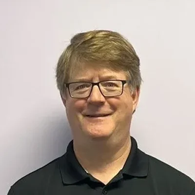 Dewayne smiling, he is wearing a black polo shirt.