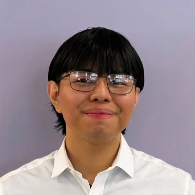 Eduardo smiling in front of a purple wall.