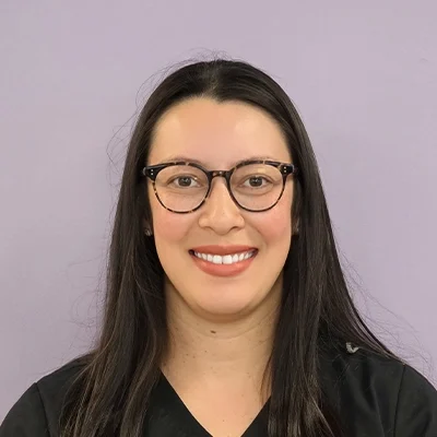 Licensed Optometrist Greyssy Haider Smiling In Front Of Purple Background