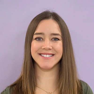 Licensed Optometrist Katherine Brown Smiling In Front Of Purple Background