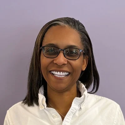 Tamara smiling in front of a purple wall.